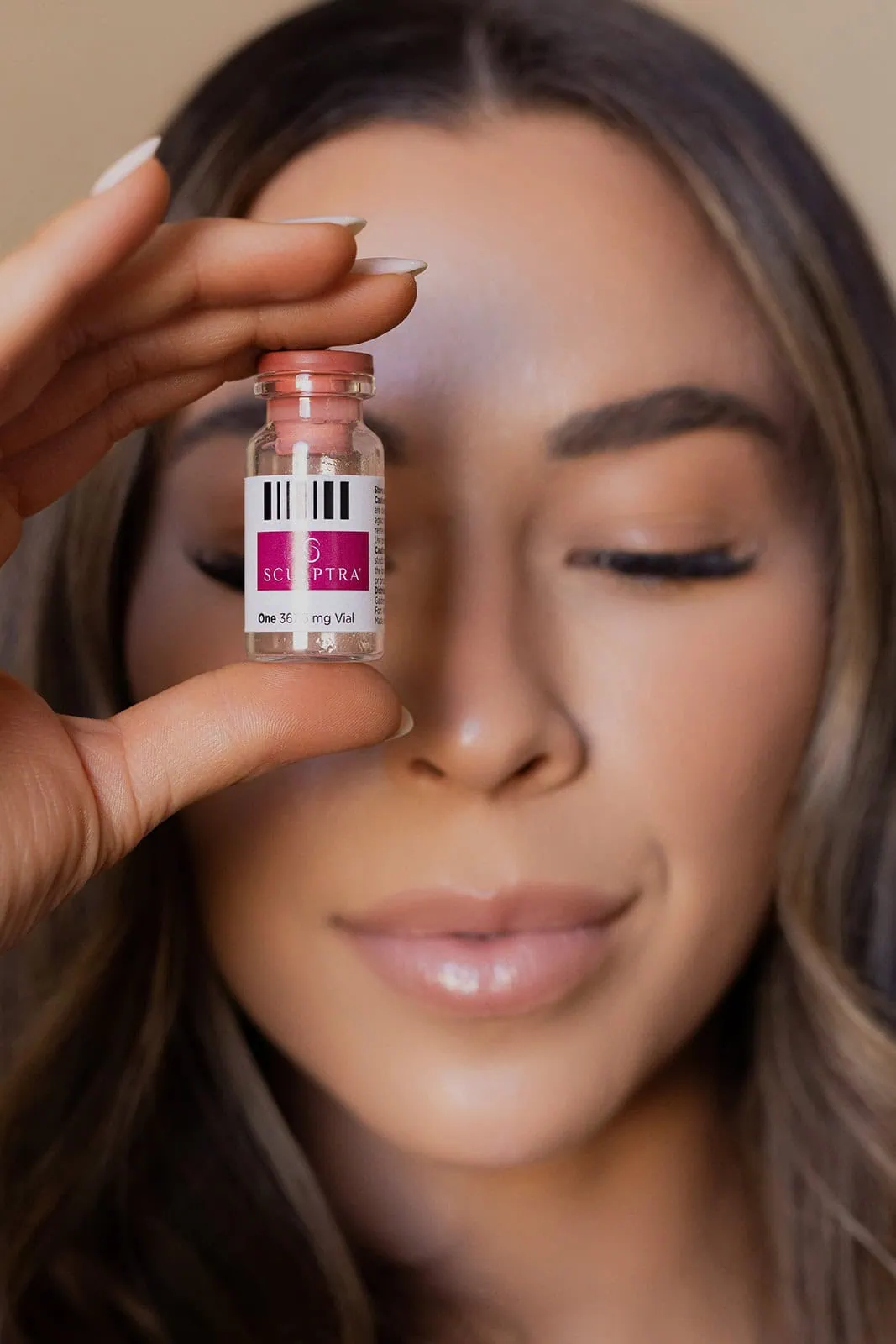 woman holding up sculptra bottle to compare the difference between sculptra and radiesse