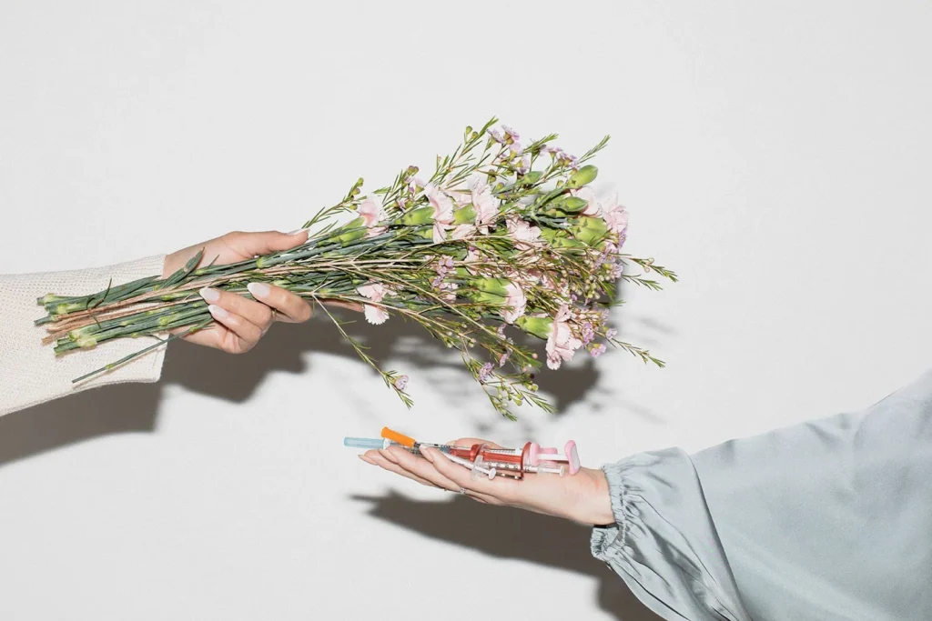 bouquet of flowers and a hand holding injectables representing prejuvenation