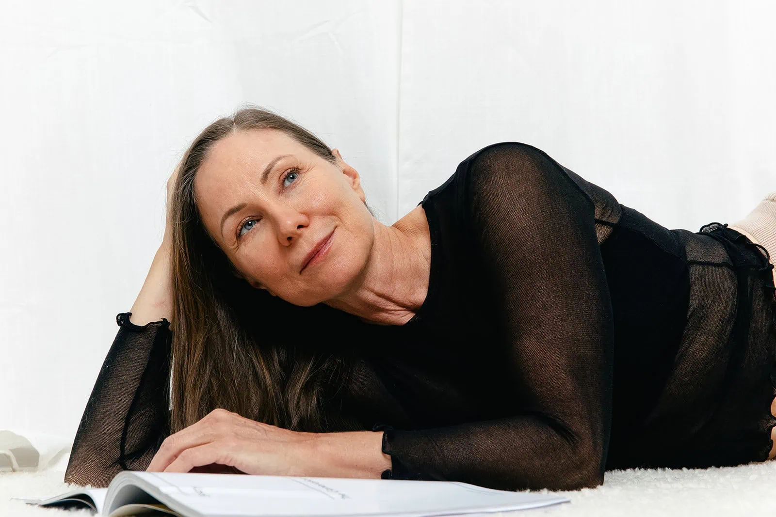 Woman resting on her side with soft lighting, showcasing the jawline and lower face often targeted in jowls treatment.