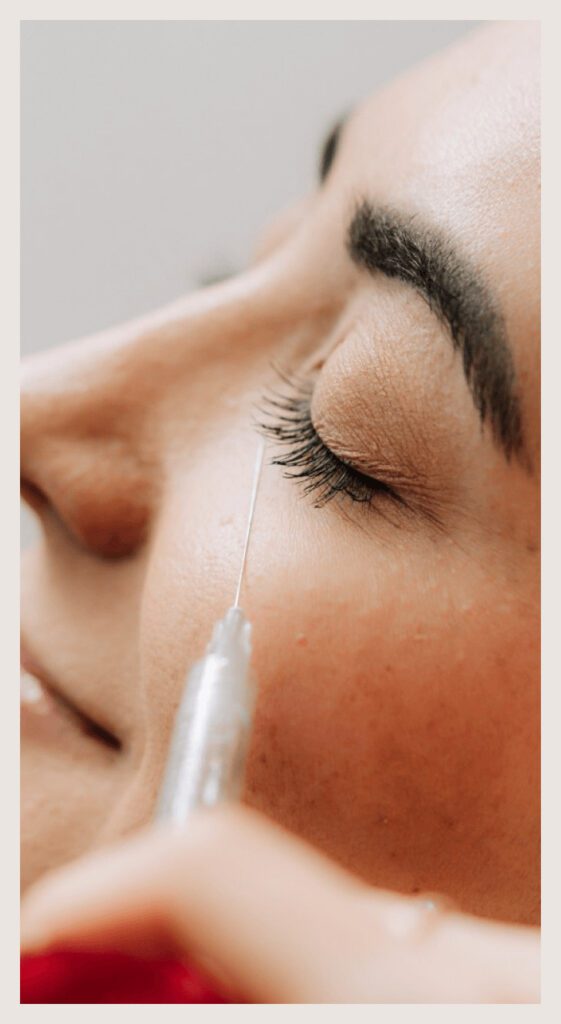 A woman's face receives a Juvederm injection below her left eye.
