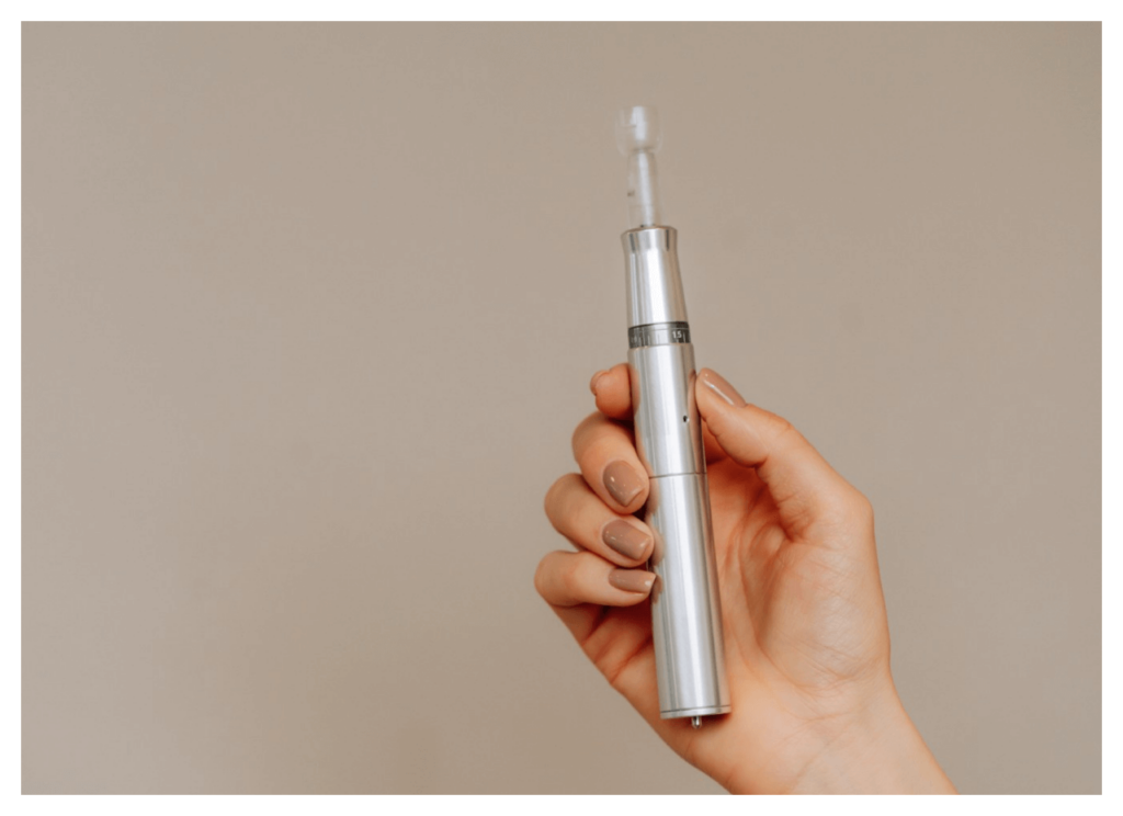A hand holding a micropen, used for microneedling treatment.